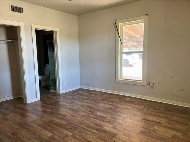 an empty room with wooden floor closet and windows