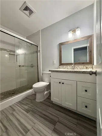 a bathroom with a granite countertop sink a toilet and shower