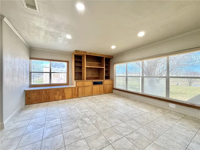 a view of an empty room with a window and kitchen view