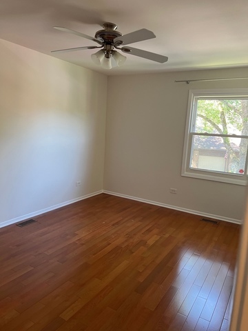 249 Shadow Bend Drive, Unit 249 Wheeling, IL 60090 - Photo 13 of 17 an empty room with wooden floor fan and windows