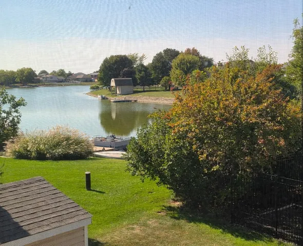 a view of a lake with a yard and large trees