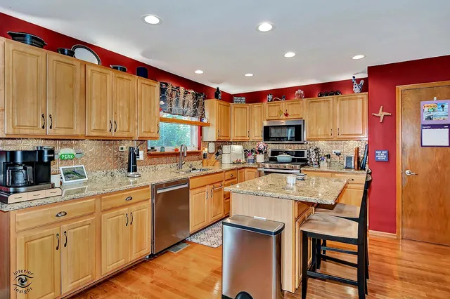 a kitchen with stainless steel appliances granite countertop a stove top oven a sink dishwasher and white cabinets with wooden floor