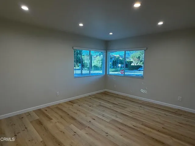 an empty room with wooden floor and windows