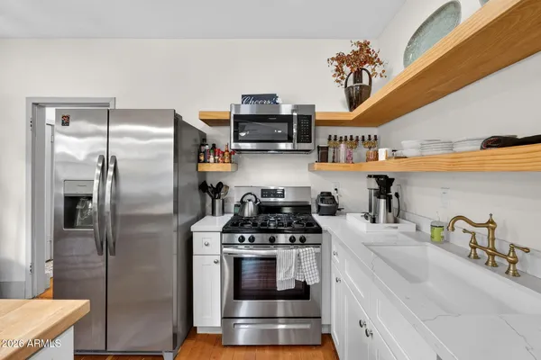 a kitchen with counter top space a sink stainless steel appliances and windows