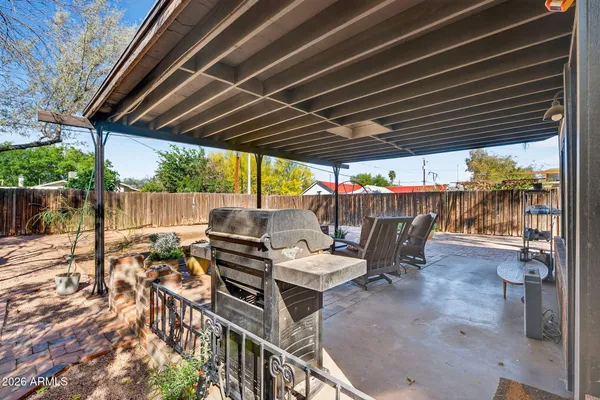 a view of a patio with table and chairs under an umbrella with wooden fence