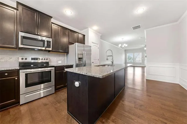 a kitchen with stainless steel appliances kitchen island granite countertop a stove a sink and a microwave