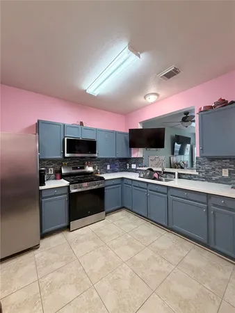 a large kitchen with a large counter top space a sink stainless steel appliances and cabinets