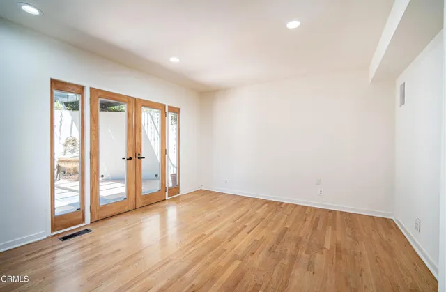 an empty room with wooden floor and windows