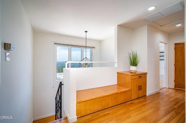 a view of a kitchen with kitchen island a window wooden floor and stainless steel appliances