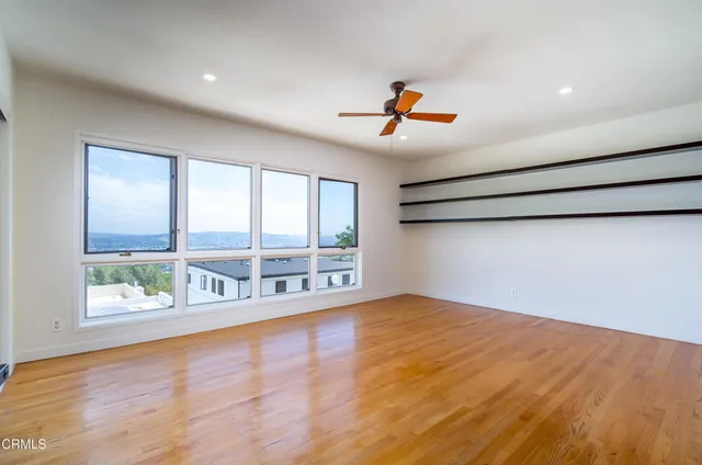 a view of an empty room with a window and wooden floor