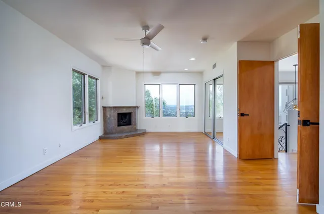 a view of an empty room with window and wooden floor