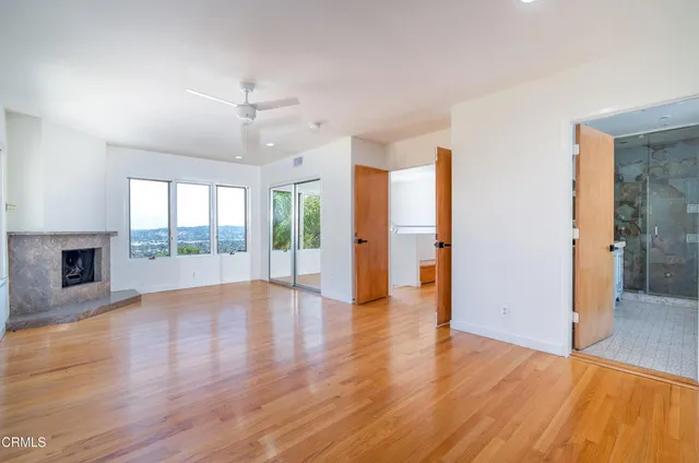 a view of an empty room with wooden floor and a fireplace