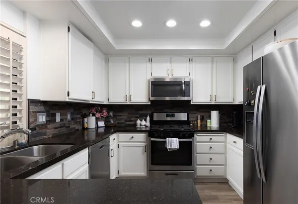 a kitchen with white cabinets and black appliances