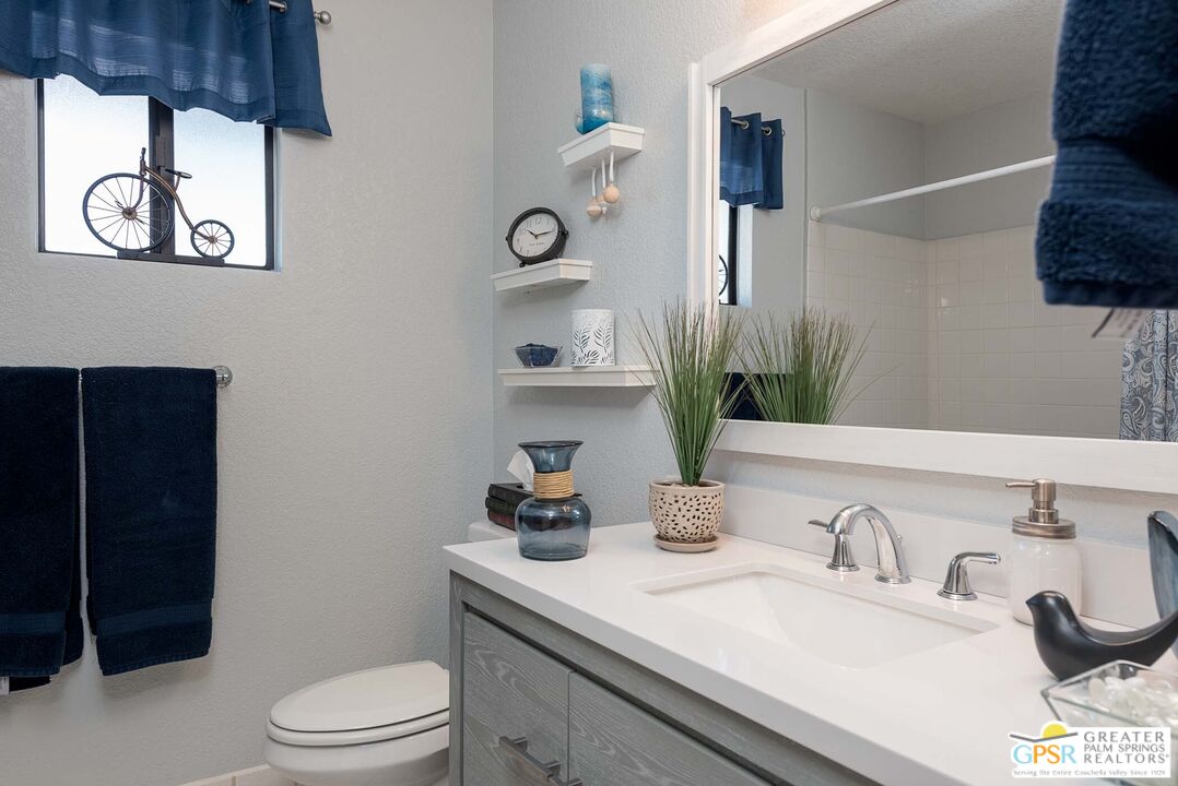 9760 Capiland Road Desert Hot Springs, CA 92240 - Photo 13 of 16 a bathroom with a granite countertop sink a toilet and mirror