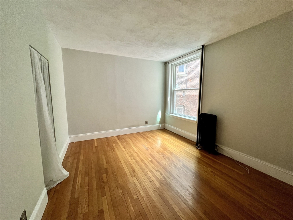 138 Fuller Street, Unit 3 Brookline, MA 02446 - Photo 11 of 27 an empty room with wooden floor and windows