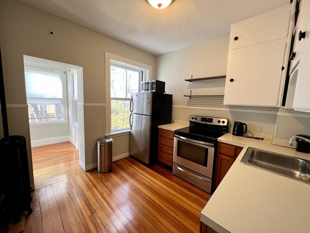 138 Fuller Street, Unit 3 Brookline, MA 02446 - Photo 2 of 27 a kitchen with a refrigerator stove and wooden floor