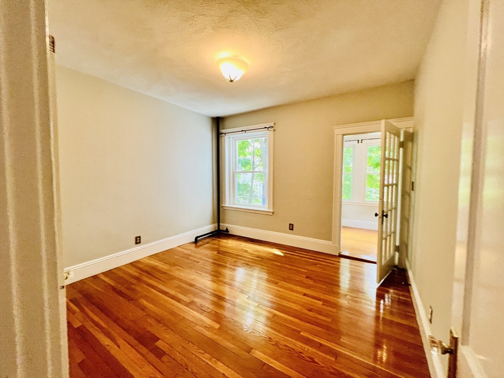 138 Fuller Street, Unit 3 Brookline, MA 02446 - Photo 22 of 27 a view of an empty room with wooden floor and a window