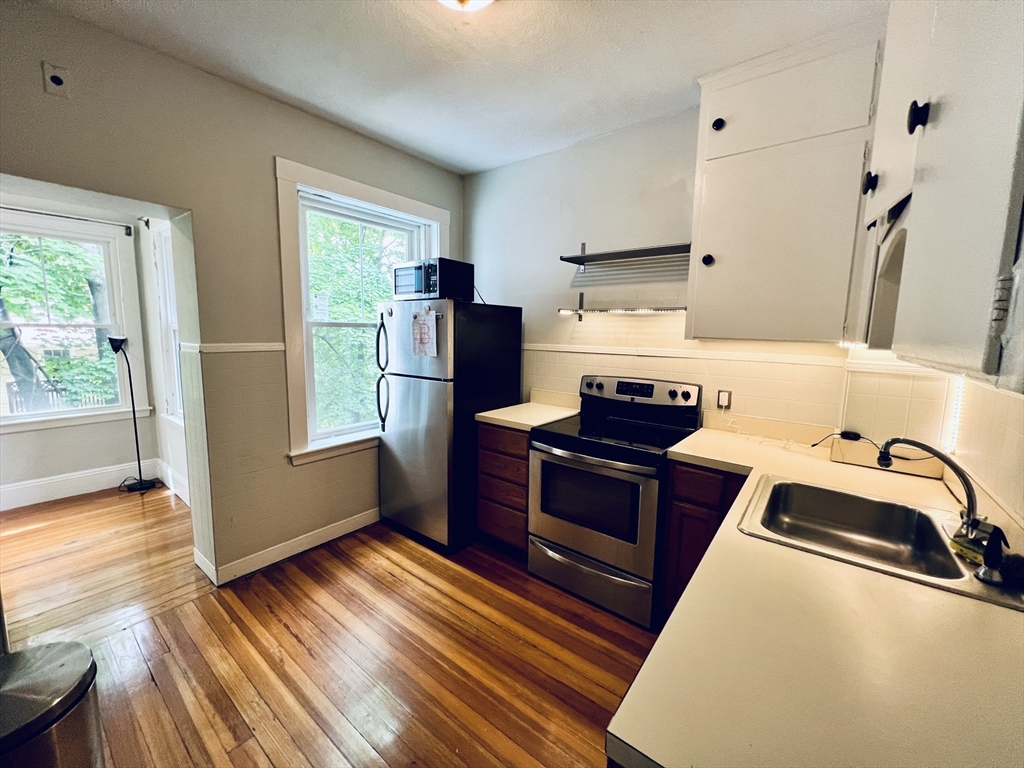 138 Fuller Street, Unit 3 Brookline, MA 02446 - Photo 4 of 27 a kitchen with stainless steel appliances granite countertop a refrigerator stove and wooden floor