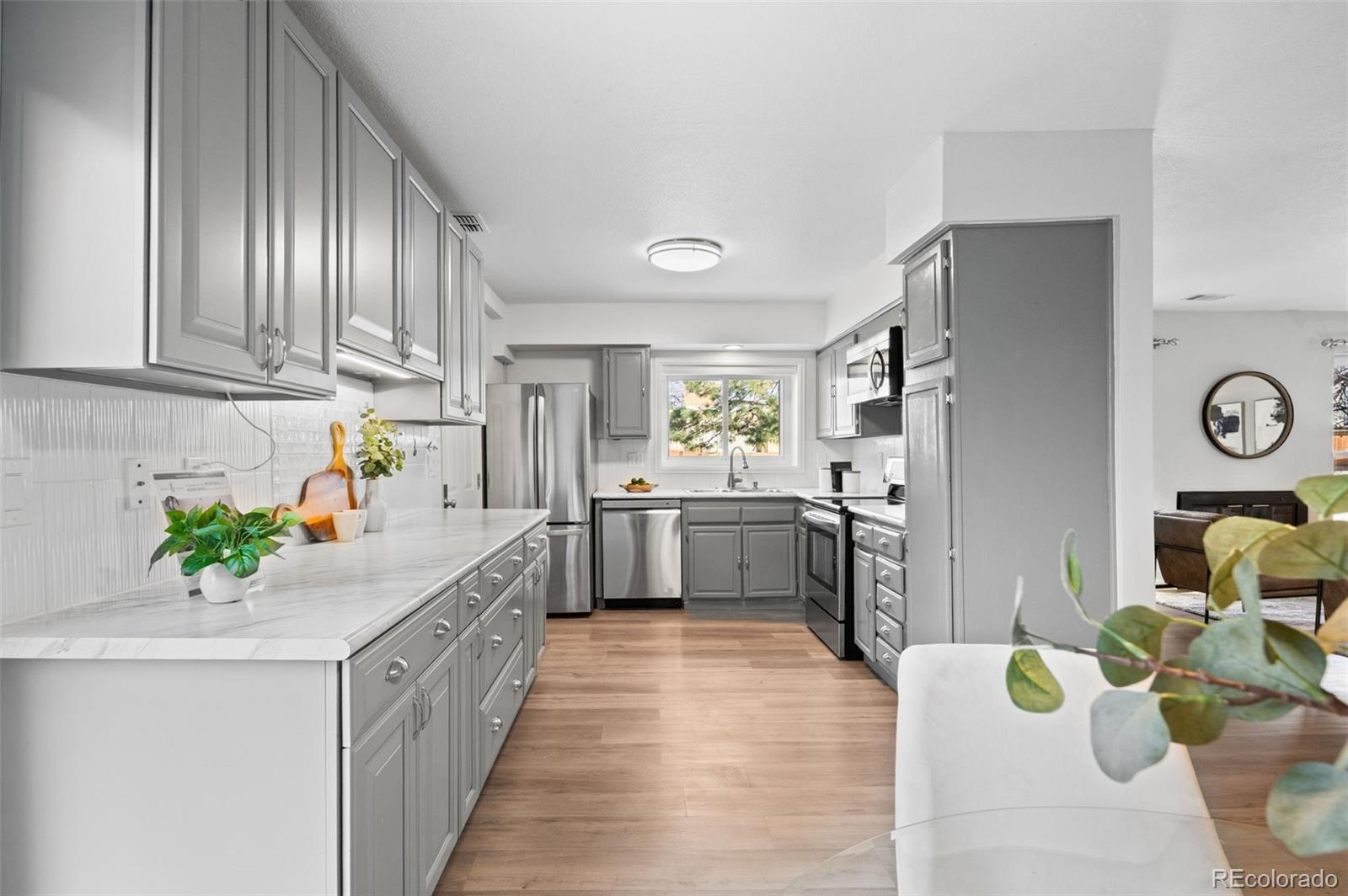 16373 East Rice Place, Unit B Aurora, CO 80015 - Photo 12 of 26 a kitchen with stainless steel appliances granite countertop a refrigerator a sink dishwasher and white cabinets with wooden floor