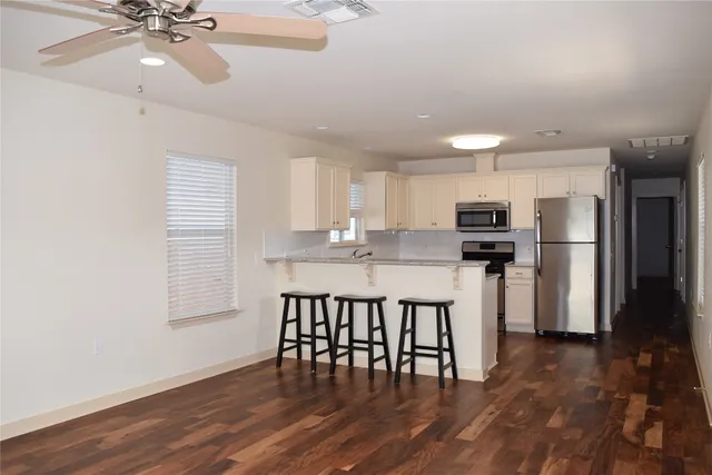 a kitchen with stainless steel appliances a dining table chairs and wooden floor