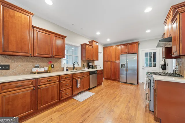 a large kitchen with stainless steel appliances granite countertop a refrigerator a sink dishwasher a oven with wooden cabinets and floor