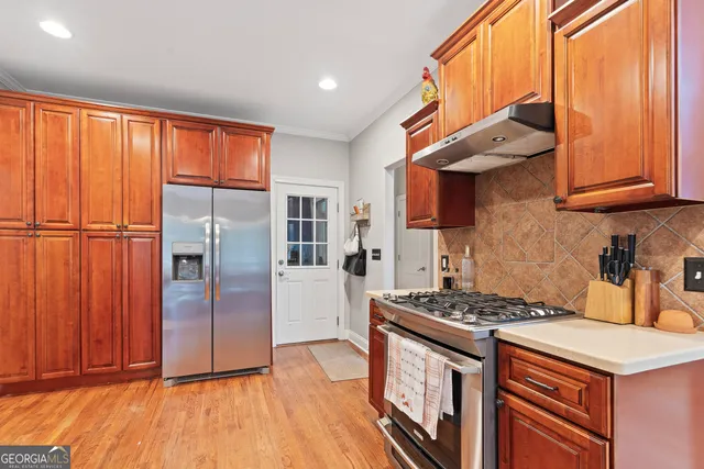 a kitchen with stainless steel appliances granite countertop a stove a refrigerator and wooden cabinets