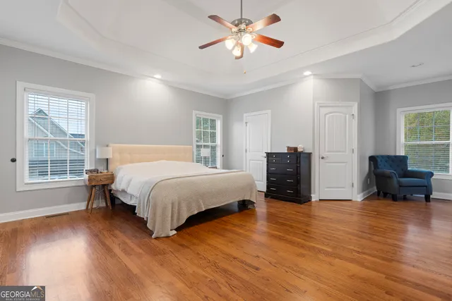 a spacious bedroom with a bed a couch and two dresser next to a window