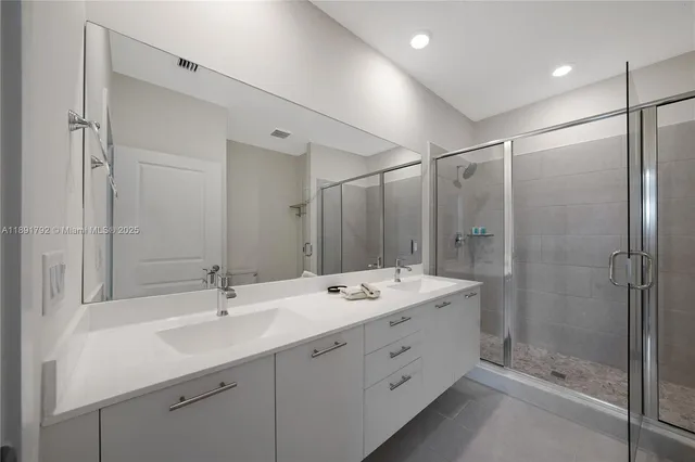 a bathroom with a double vanity sink mirror and shower