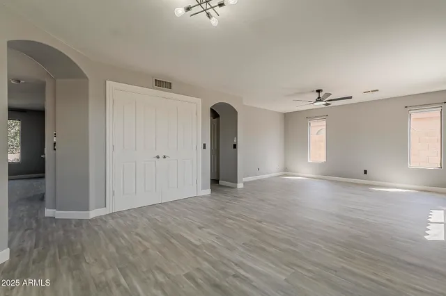 a view of empty room with wooden floor and fan