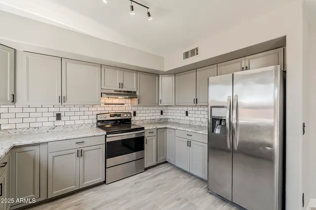 a kitchen with stainless steel appliances granite countertop a sink stove and refrigerator