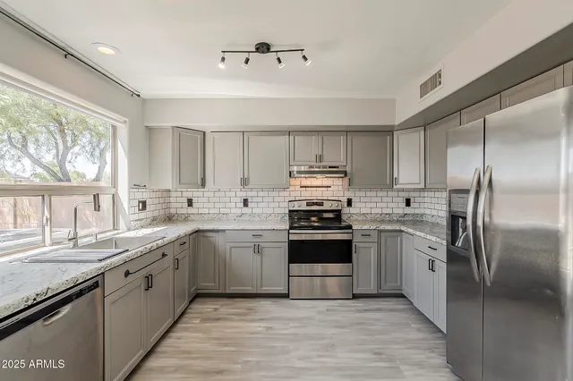 a kitchen with stainless steel appliances granite countertop a refrigerator and a sink