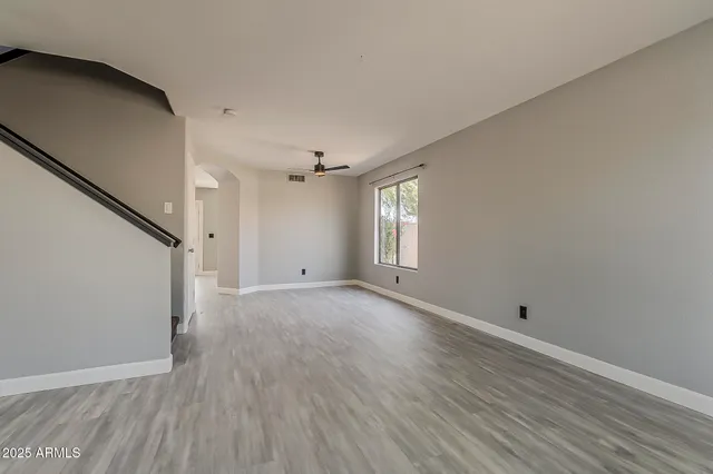 a view of empty room with wooden floor and fan