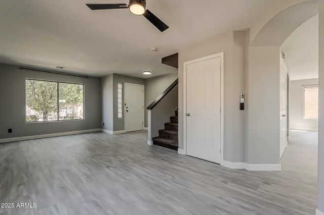 an empty room with wooden floor cabinet and windows