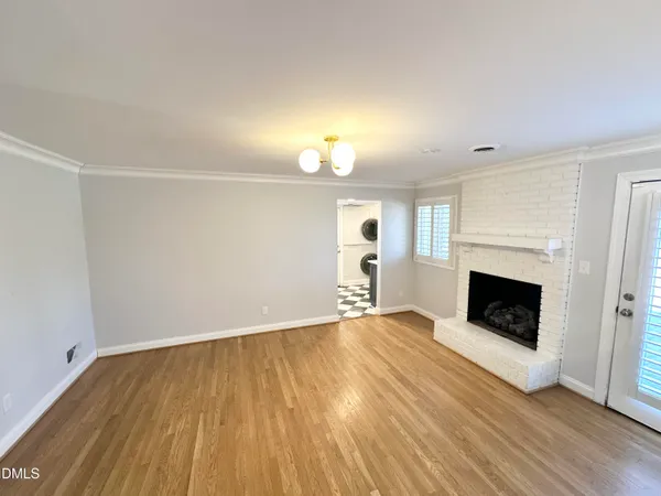 an empty room with wooden floor fireplace and windows