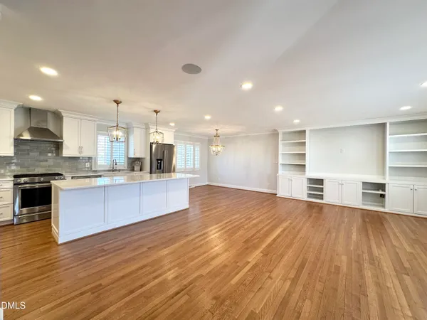a large kitchen with stainless steel appliances granite countertop a large counter top and a stove top oven with wooden floor
