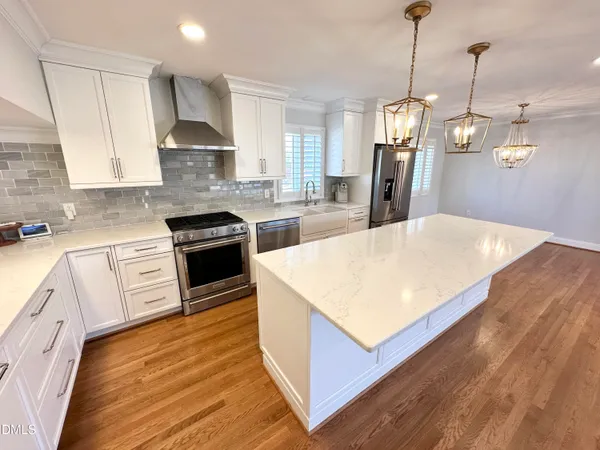 a kitchen with stainless steel appliances kitchen island granite countertop a sink a stove and a wooden floors