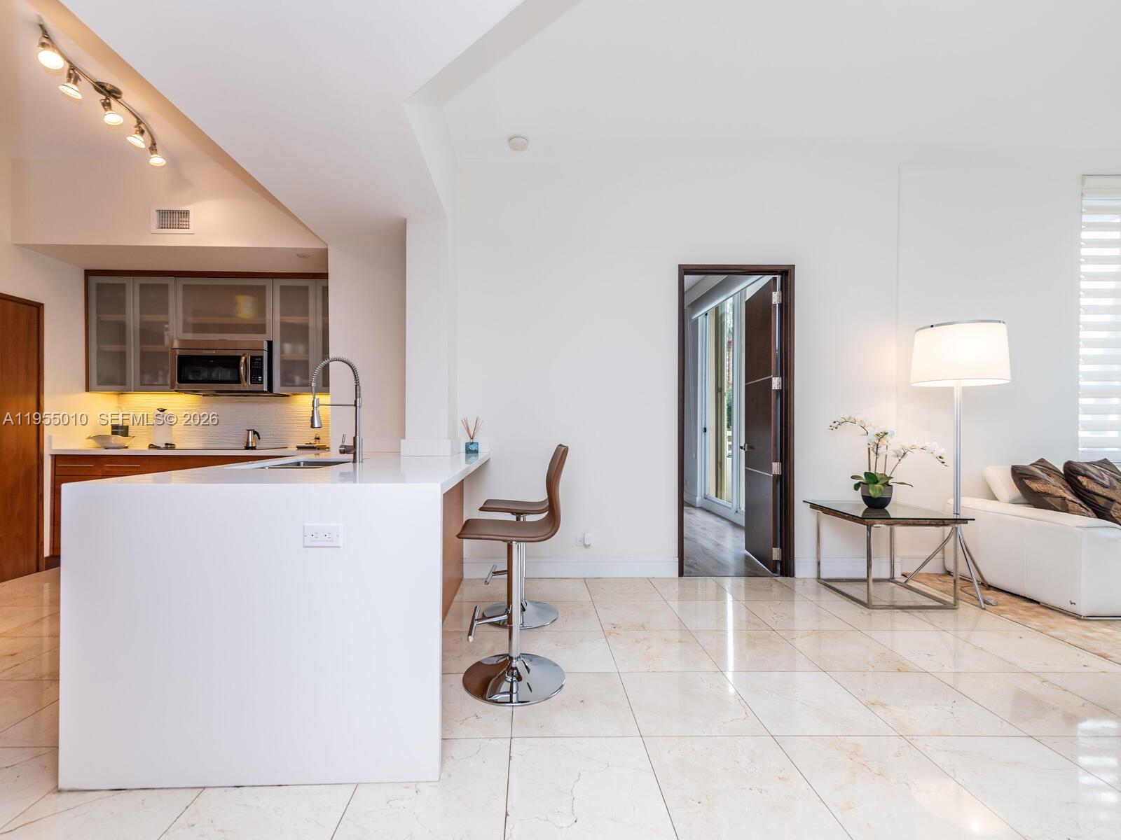 888 Brickell Key Drive, Unit 210 Miami, FL 33131 - Photo 11 of 84 a living room with furniture a flat screen tv and a refrigerator
