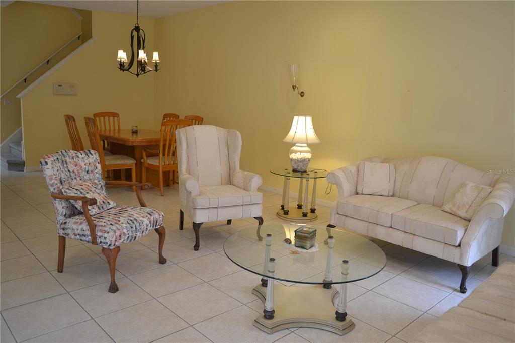11117 Kapok Grand Circle Madeira Beach, FL 33708 - Photo 13 of 62 a living room with furniture a chandelier and a dining table
