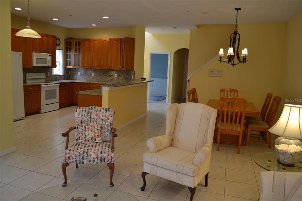 11117 Kapok Grand Circle Madeira Beach, FL 33708 - Photo 15 of 62 a kitchen with stainless steel appliances kitchen island granite countertop a refrigerator a stove a sink with a dining table and chairs