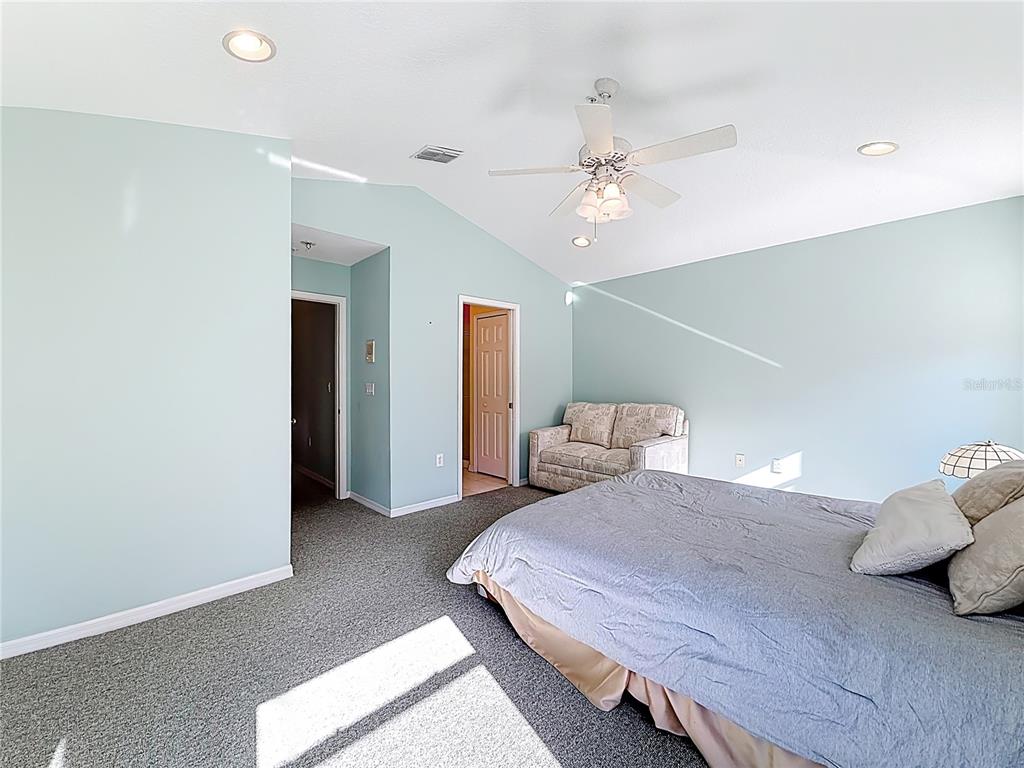 11117 Kapok Grand Circle Madeira Beach, FL 33708 - Photo 31 of 62 a bedroom with a large bed and a ceiling fan
