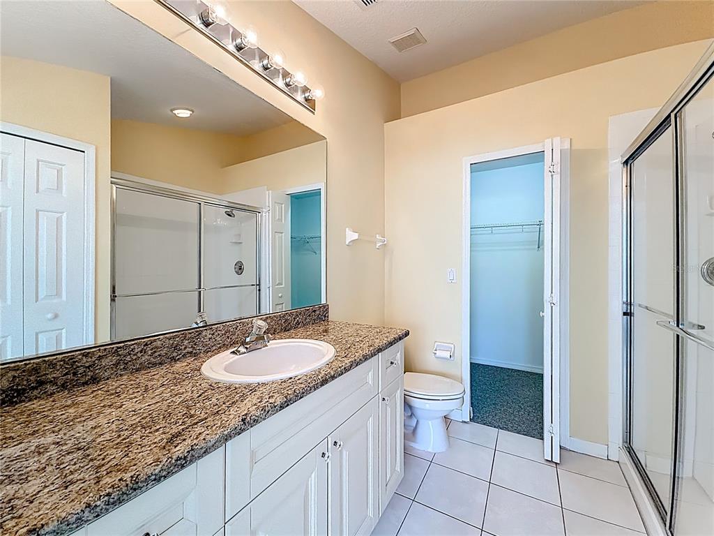 11117 Kapok Grand Circle Madeira Beach, FL 33708 - Photo 32 of 62 a bathroom with a granite countertop sink a mirror and a toilet