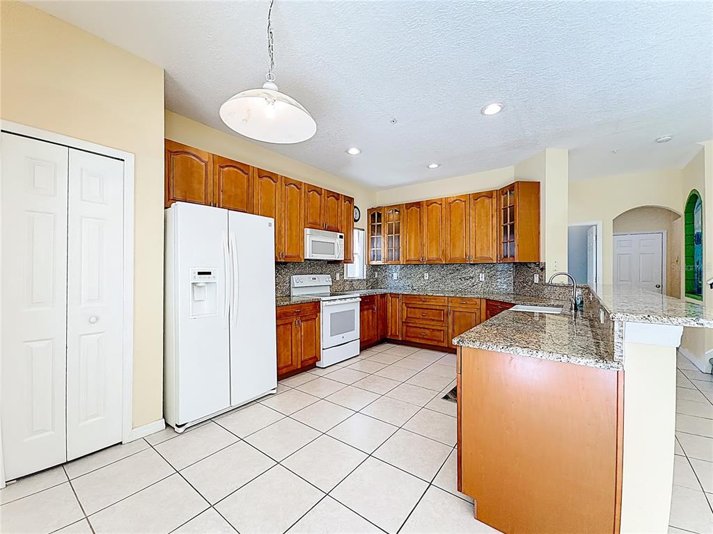 11117 Kapok Grand Circle Madeira Beach, FL 33708 - Photo 9 of 62 a kitchen with stainless steel appliances granite countertop a refrigerator a sink dishwasher and white cabinets with wooden floor