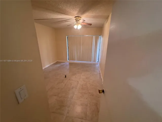 an empty room with a ceiling fan and a window