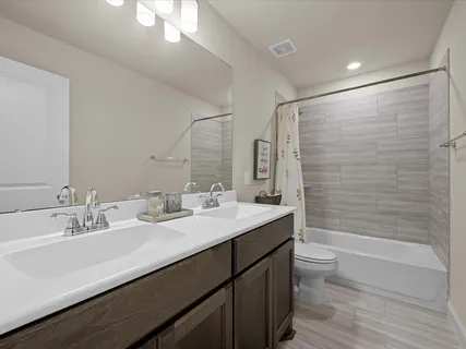 a bathroom with a double vanity sink toilet mirror and bathtub