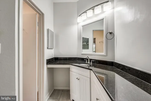 a bathroom with a granite countertop sink and a mirror