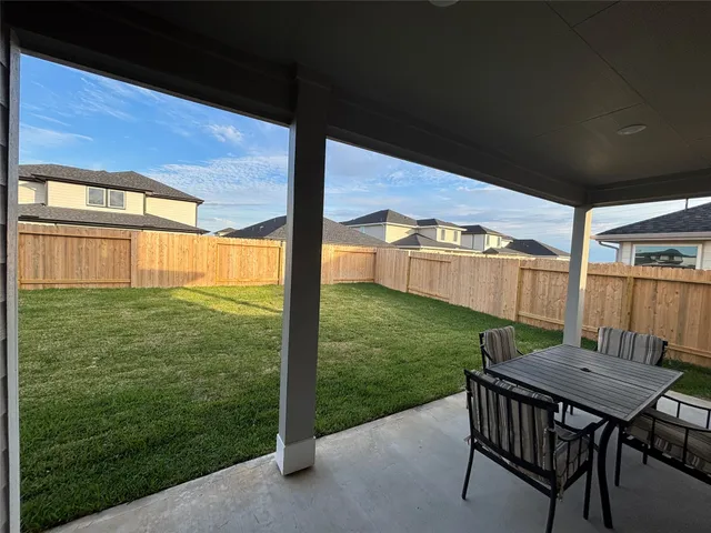 a view of a backyard with table and chairs potted plants with wooden floor and fence