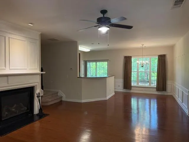 a view of an empty room with wooden floor and a fireplace