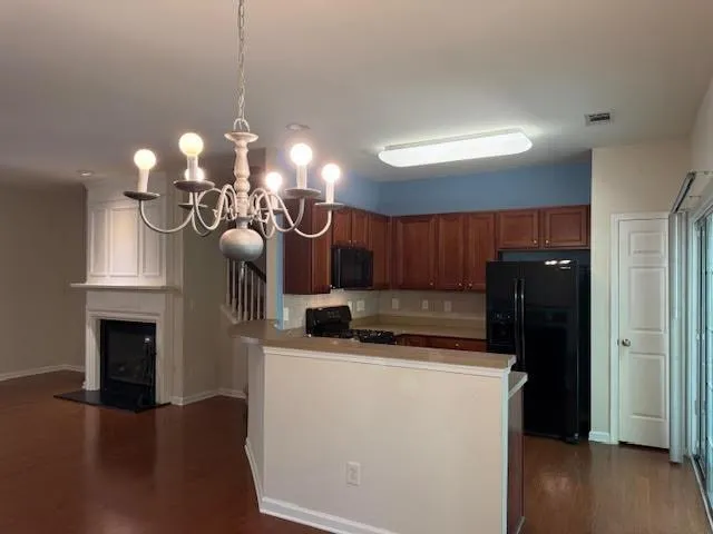 a kitchen with stainless steel appliances granite countertop a refrigerator a sink dishwasher a dining table and chairs with wooden floor