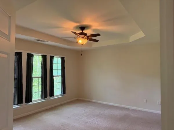 an empty room with ceiling fan and window
