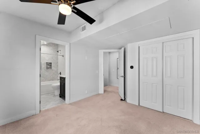 an empty room with fan and hallway